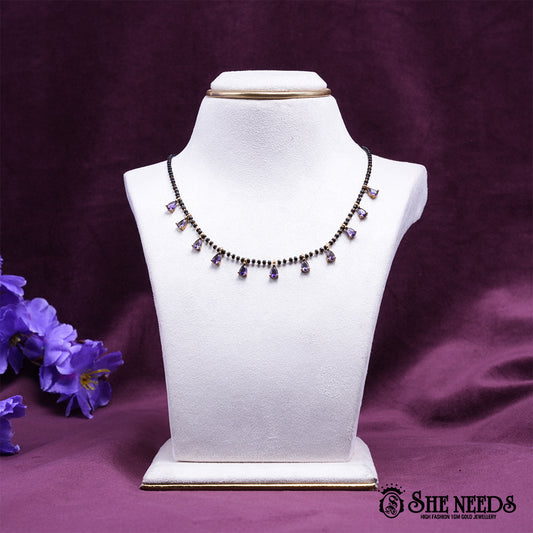 Black bead mangalsutra necklace featuring graceful purple pear-shaped stone drops set in a gold-tone finish.|She Needs Jewellery