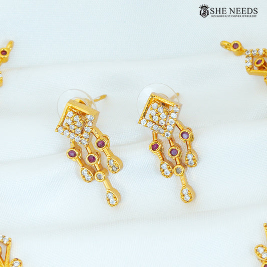 Close-up of geometric ruby and white stone gold long drop earrings with diamond-shaped detailing and dangling accents|She Needs Jewellery