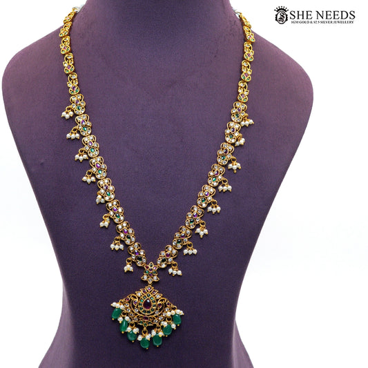 Long royal temple necklace featuring intricate gold-toned motifs, green and ruby-style stones, sparkling white stones and pearl drop embellishments|She Needs Jewellery