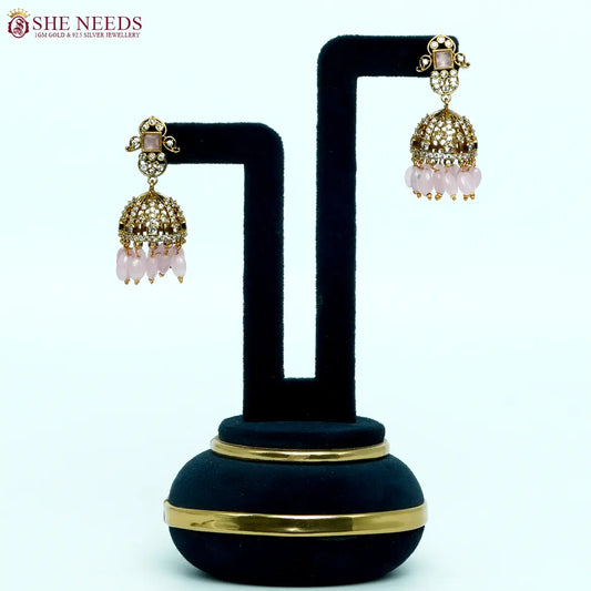 Gold-tone dome jhumka earrings with sparkling white stones, blush pink square center stones, and light-pink bead drops, ideal for weddings and festive occasions. | She Needs Jewellery