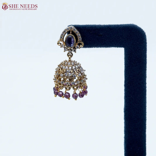 Royal Stone Antique Purple Jhumka Earrings featuring sparkling American Diamonds, antique gold detailing, purple stone centerpiece, and purple crystal bead drops.|She Needs Jewellery