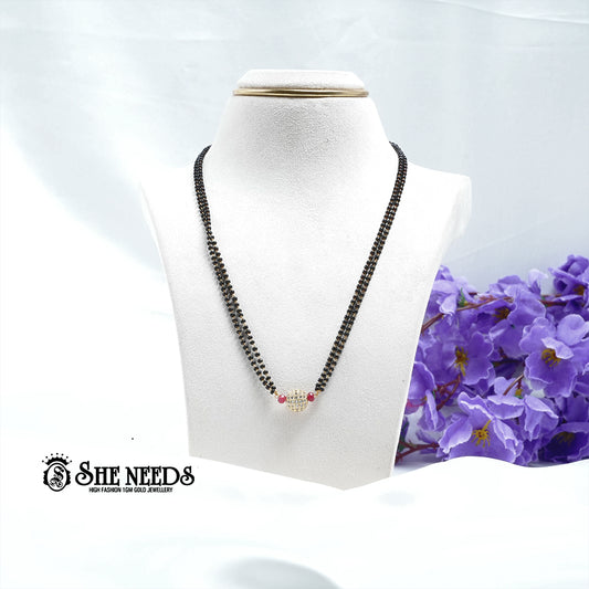 Ruby red dual-string mangalsutra with black beads, CZ-studded spherical pendant, red bead accents, and gold-tone finish displayed on a white jewelry bust |She Needs Jewellery