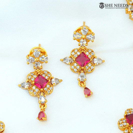 Close-up of ruby stone floral gold-plated earrings with sparkling white AD stones and dangling ruby accents|She Needs Jewellery