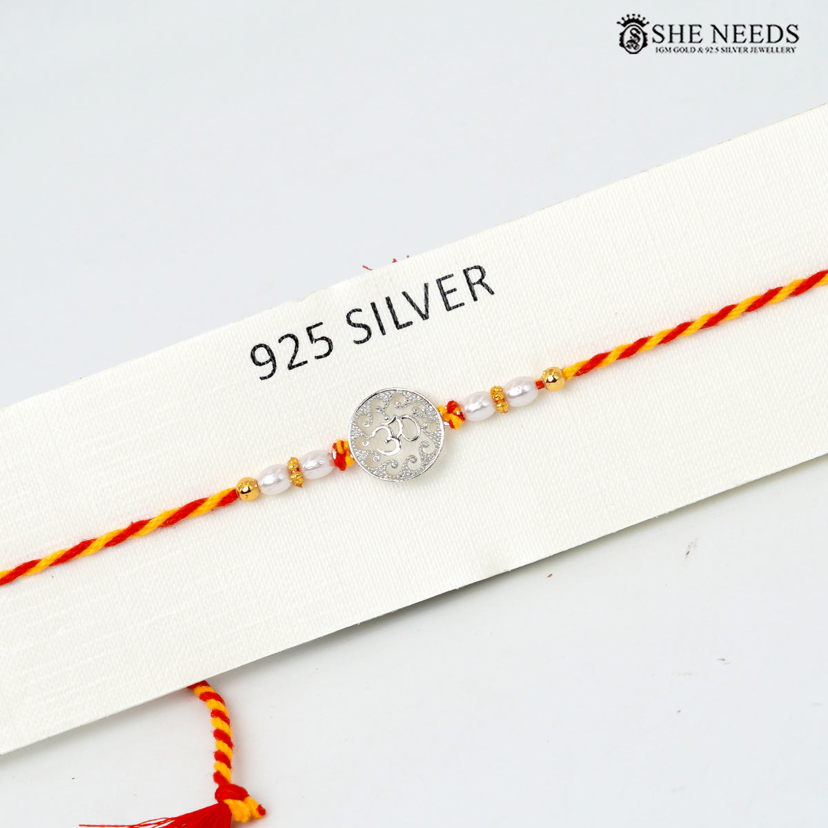 925 silver Om Rakhi with pearl beads and red-yellow braided thread styled with festive decor|She Needs Jewellery

