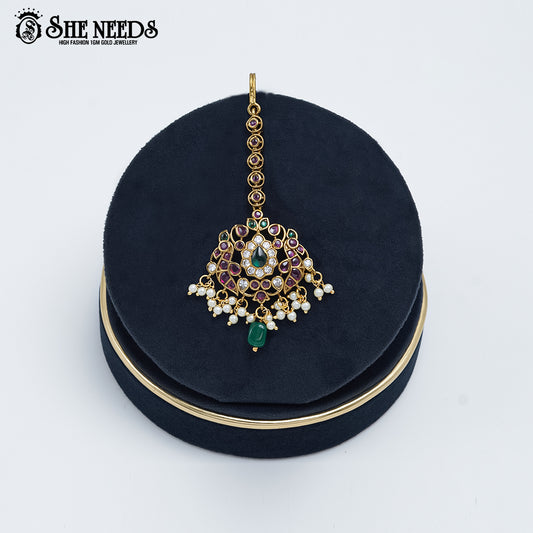 Antique Floral Maang Tikka featuring ruby-colored stones, green accents, sparkling American Diamonds, pearl drops, and an antique gold finish.|She Needs Jewellery
