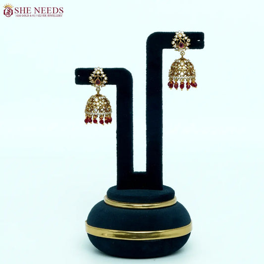 Antique gold plated jhumka earrings with white zircon stones and ruby red bead drops for women.|She Needs J Jewellery