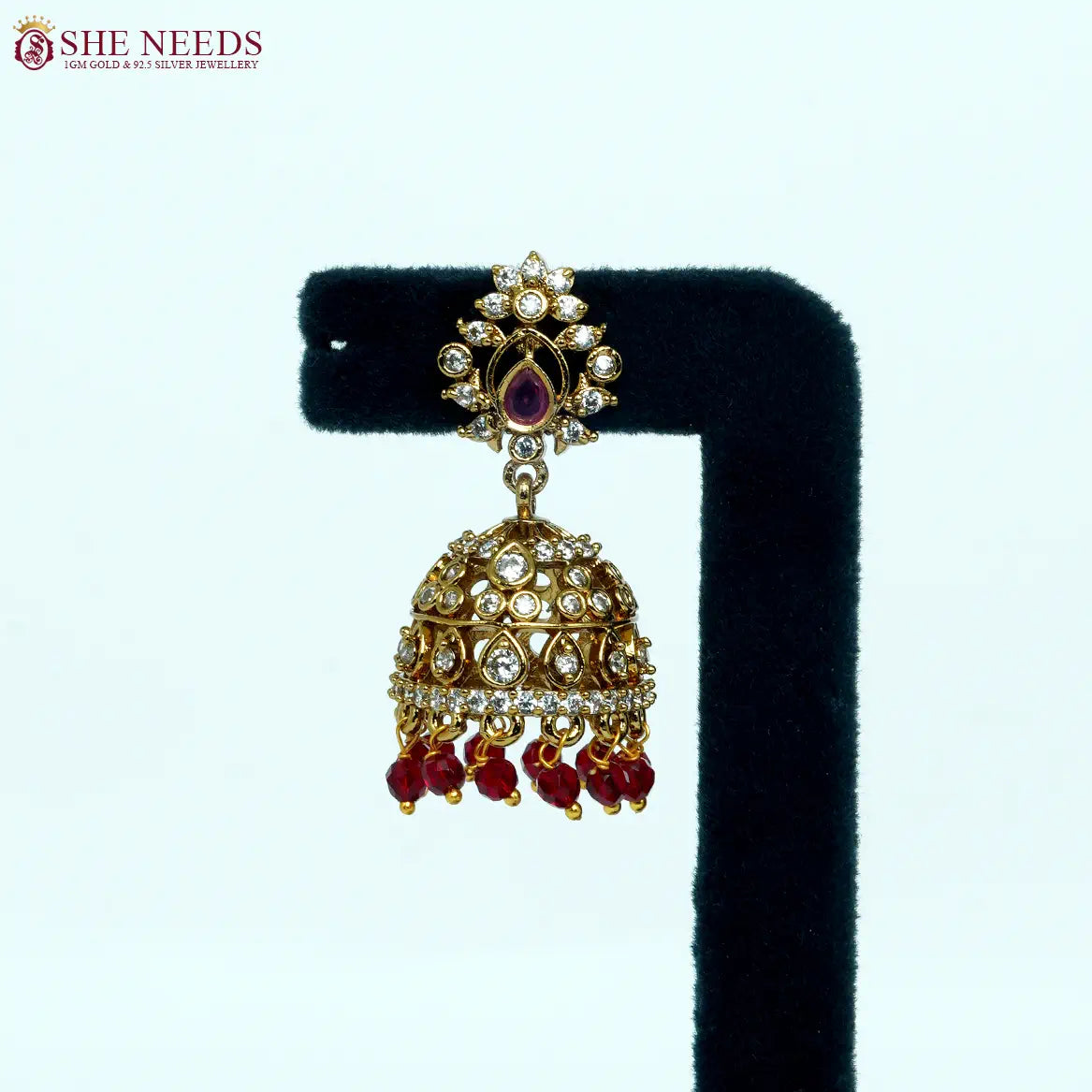Antique gold plated jhumka earrings with white zircon stones and ruby red bead drops for women.|She Needs J Jewellery