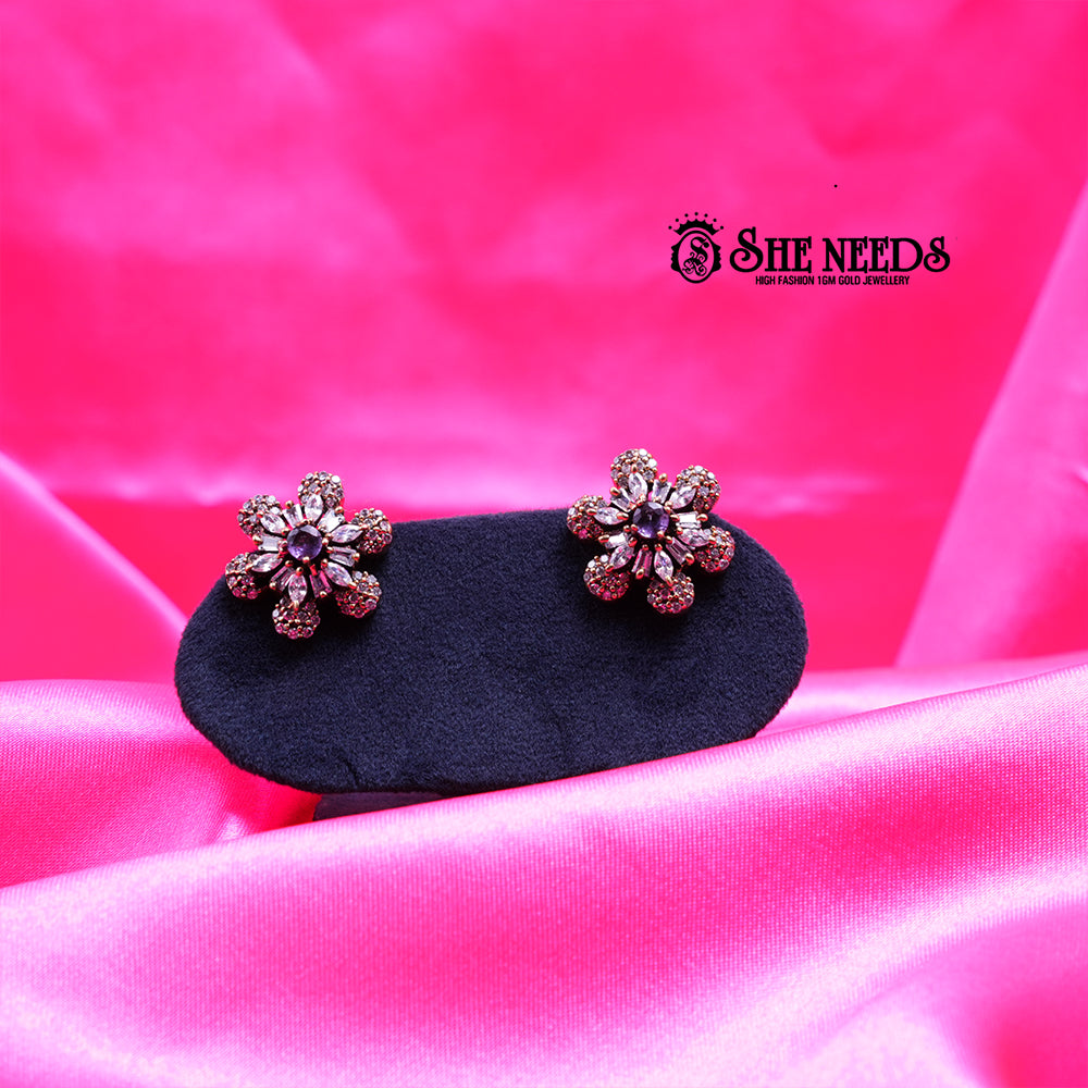 Antique gold daisy stud earrings featuring sparkling CZ stones and a rich purple center stone in a floral design.|She Needs Jewellery
