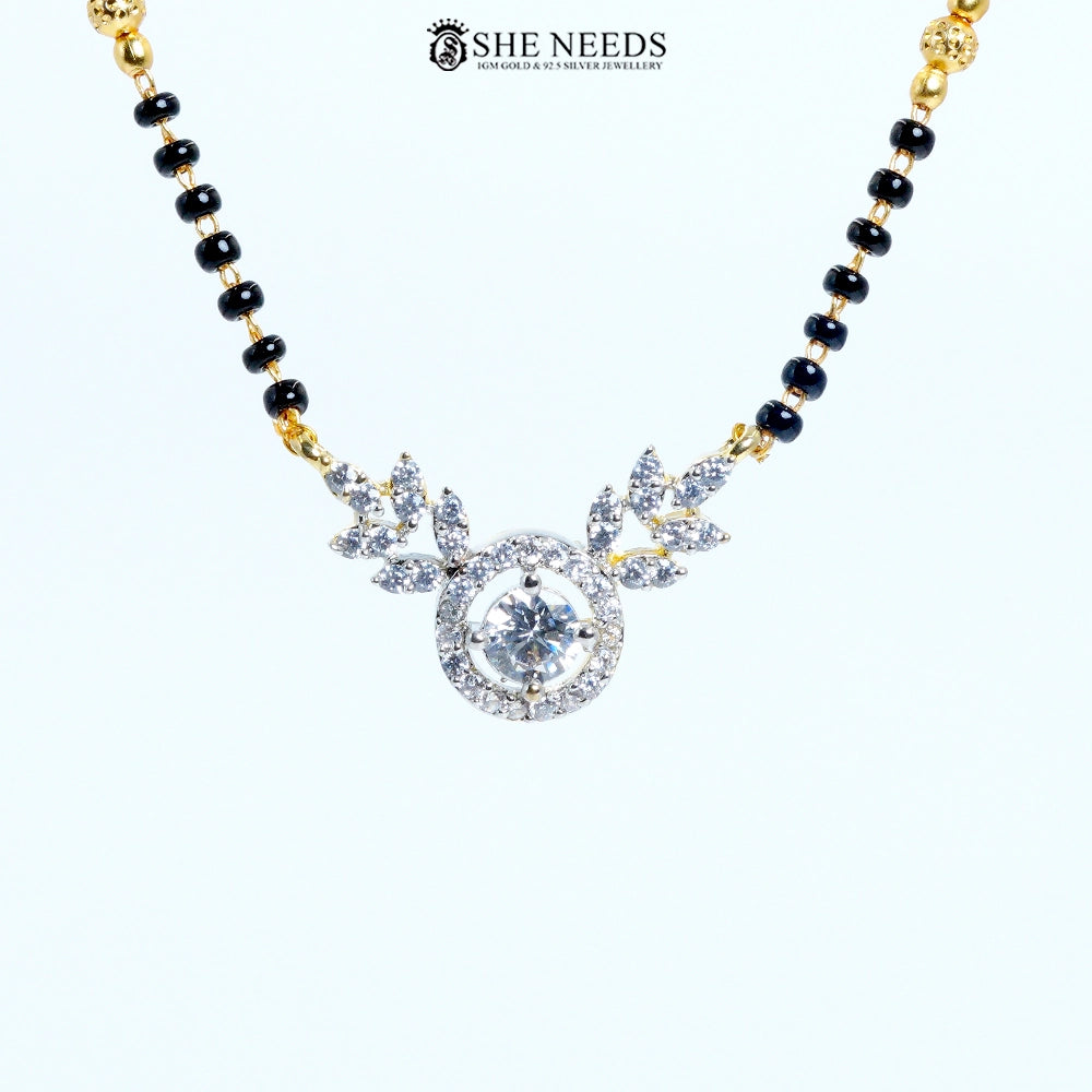 Close-up of Anvika Gold Plated AD Leaf Mangalsutra featuring a round American Diamond pendant with leaf motifs and black bead chain.|She Needs Jewellery
