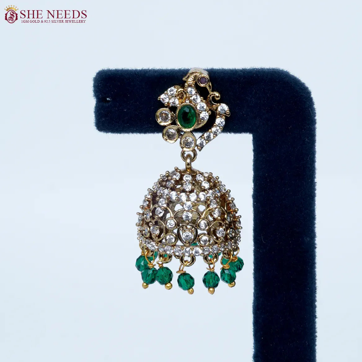 Bloomstone Green AD Jhumka Earrings featuring sparkling American Diamonds, antique gold detailing, green center stone, and matching green crystal drops.|She Needs Jewellery