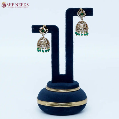 Bloomstone Green AD Jhumka Earrings featuring sparkling American Diamonds, antique gold detailing, green center stone, and matching green crystal drops.|She Needs Jewellery
