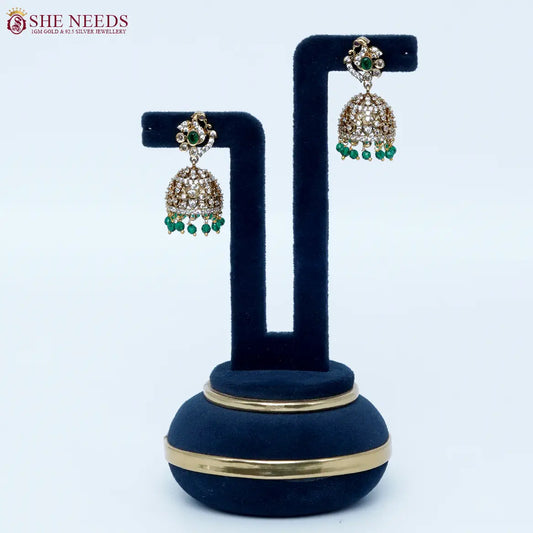Bloomstone Green AD Jhumka Earrings featuring sparkling American Diamonds, antique gold detailing, green center stone, and matching green crystal drops.|She Needs Jewellery
