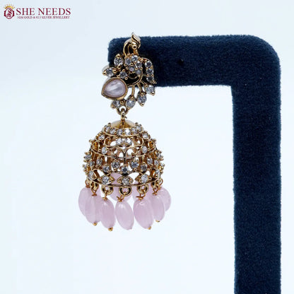 Bloomstone Light Pink AD Jhumka Earrings featuring sparkling American Diamonds, antique gold detailing, light pink center stone, and matching light pink crystal drops.|She Needs Jewellery
