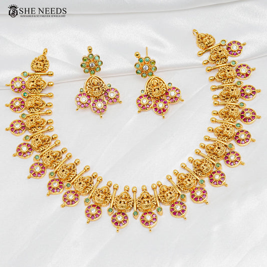 Classic Temple Lakshmi Necklace Set with matching floral earrings featuring Lakshmi motifs, ruby and green stones, and antique gold finish | She Needs Jewellery