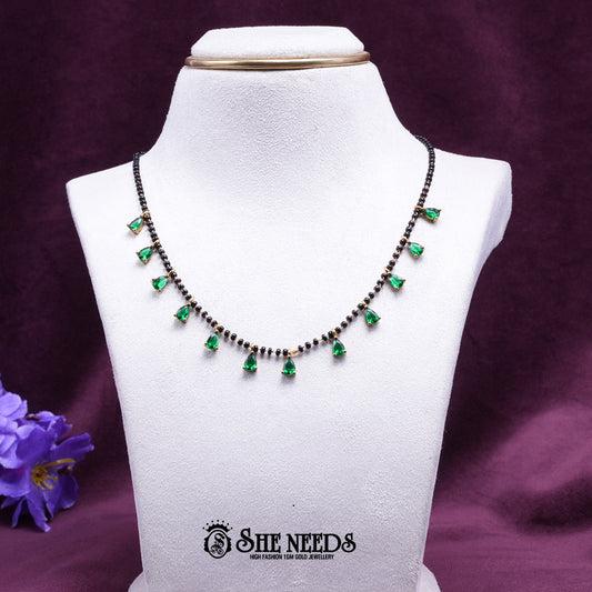 Black bead mangalsutra necklace featuring elegant green pear-shaped stone drops set in a gold-tone finish.|She Needs Jewellery
