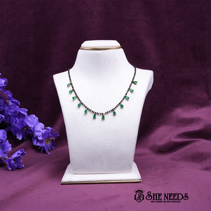 Black bead mangalsutra necklace featuring elegant green pear-shaped stone drops set in a gold-tone finish.|She Needs Jewellery
