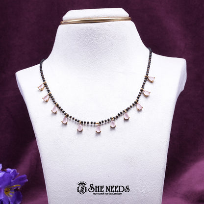 Black bead mangalsutra necklace featuring delicate light pink pear-shaped stone drops set in a gold-tone finish.|She Needs Jewellery
