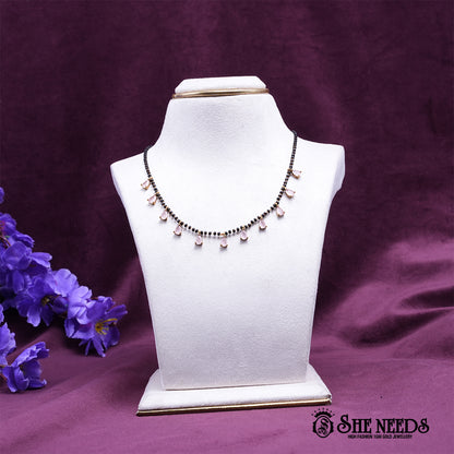 Black bead mangalsutra necklace featuring delicate light pink pear-shaped stone drops set in a gold-tone finish.|She Needs Jewellery
