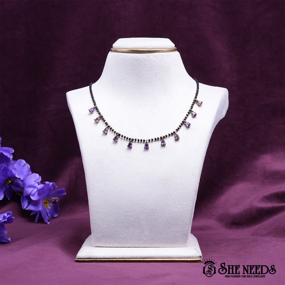 Black bead mangalsutra necklace featuring graceful purple pear-shaped stone drops set in a gold-tone finish.|She Needs Jewellery
