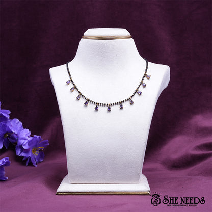 Black bead mangalsutra necklace featuring graceful purple pear-shaped stone drops set in a gold-tone finish.|She Needs Jewellery
