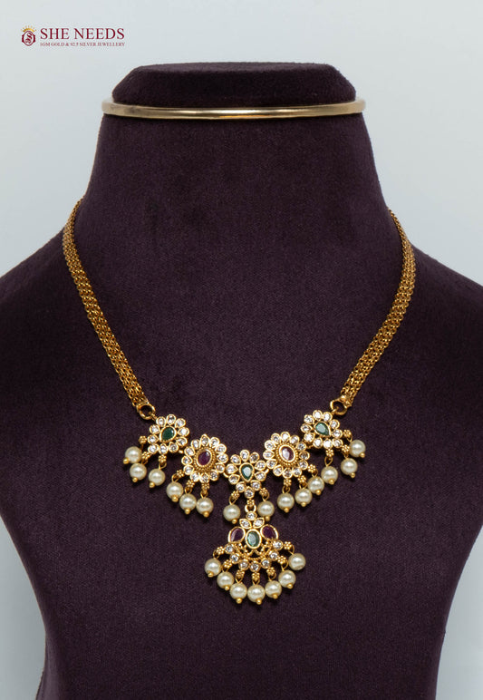 Gold-plated floral cascade necklace featuring pink and green stones, sparkling American Diamonds, pearl drops, and an elegant traditional pendant design for women.|She Needs Jewellery
