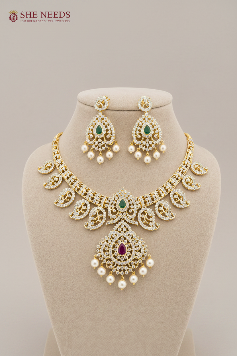 Luxury emerald green American diamond bridal necklace set with pearl drop earrings in gold finish displayed on beige mannequin.