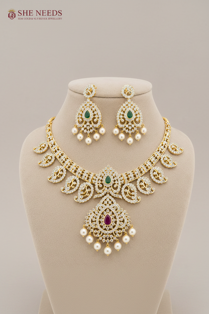 Luxury emerald green American diamond bridal necklace set with pearl drop earrings in gold finish displayed on beige mannequin.