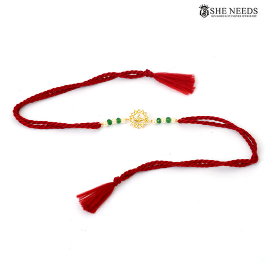 Full view of gold-plated floral Rakhi with green beads, pearl accents, red braided thread and tassels|She Needs Jewellery

