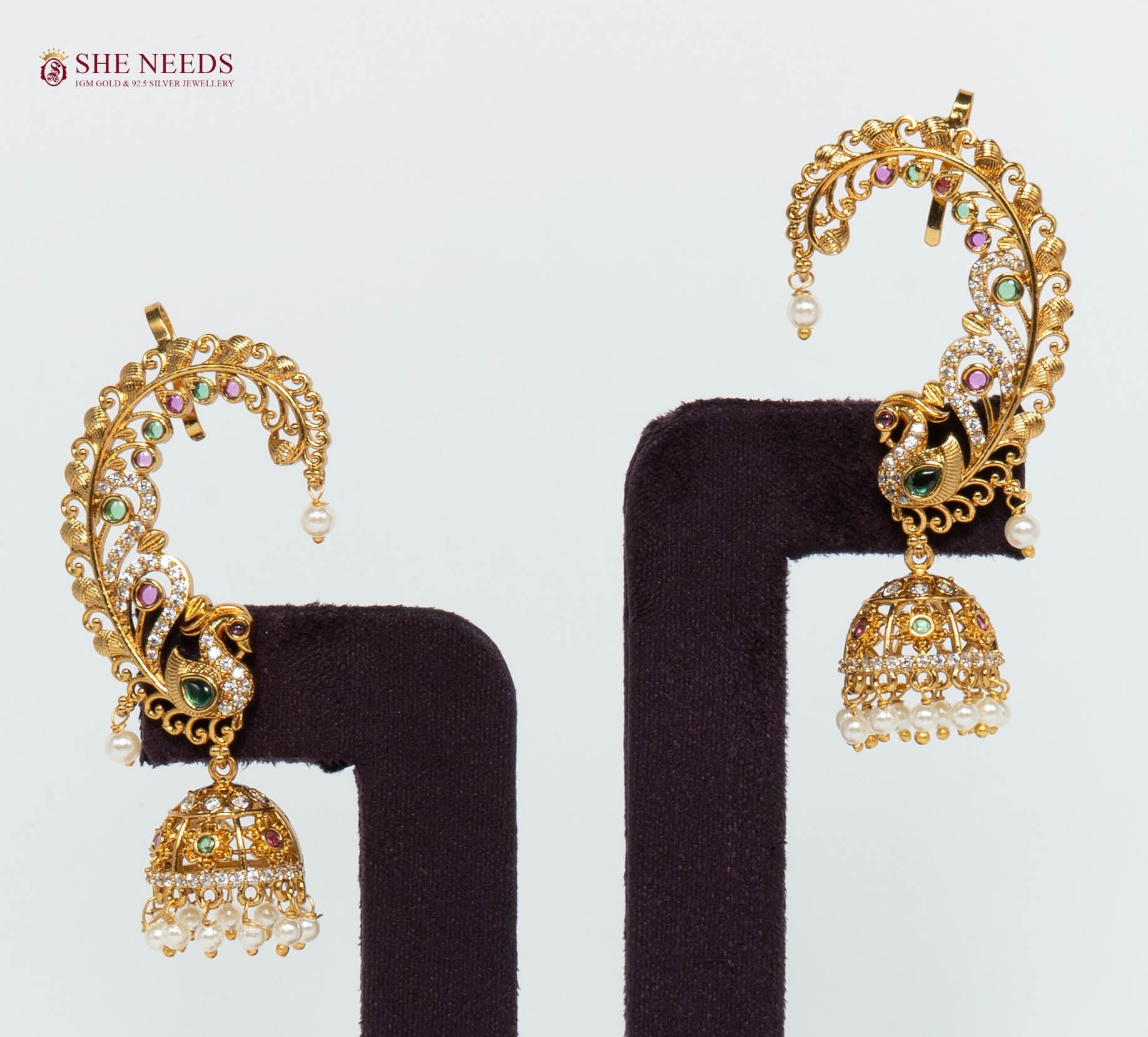 Gold-plated peacock ear cuff jhumka earrings featuring American Diamonds, multicolor stones, intricate filigree detailing, and pearl drop danglers for bridal and festive wear.|She Needs Jewellery
