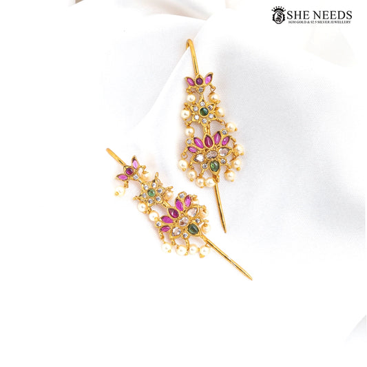 Gold finish temple design ear cuff earrings featuring ruby-pink stones, emerald-green accents, sparkling kundan stones, floral motifs, and elegant pearl drops on a white fabric background|She Needs Jewellery