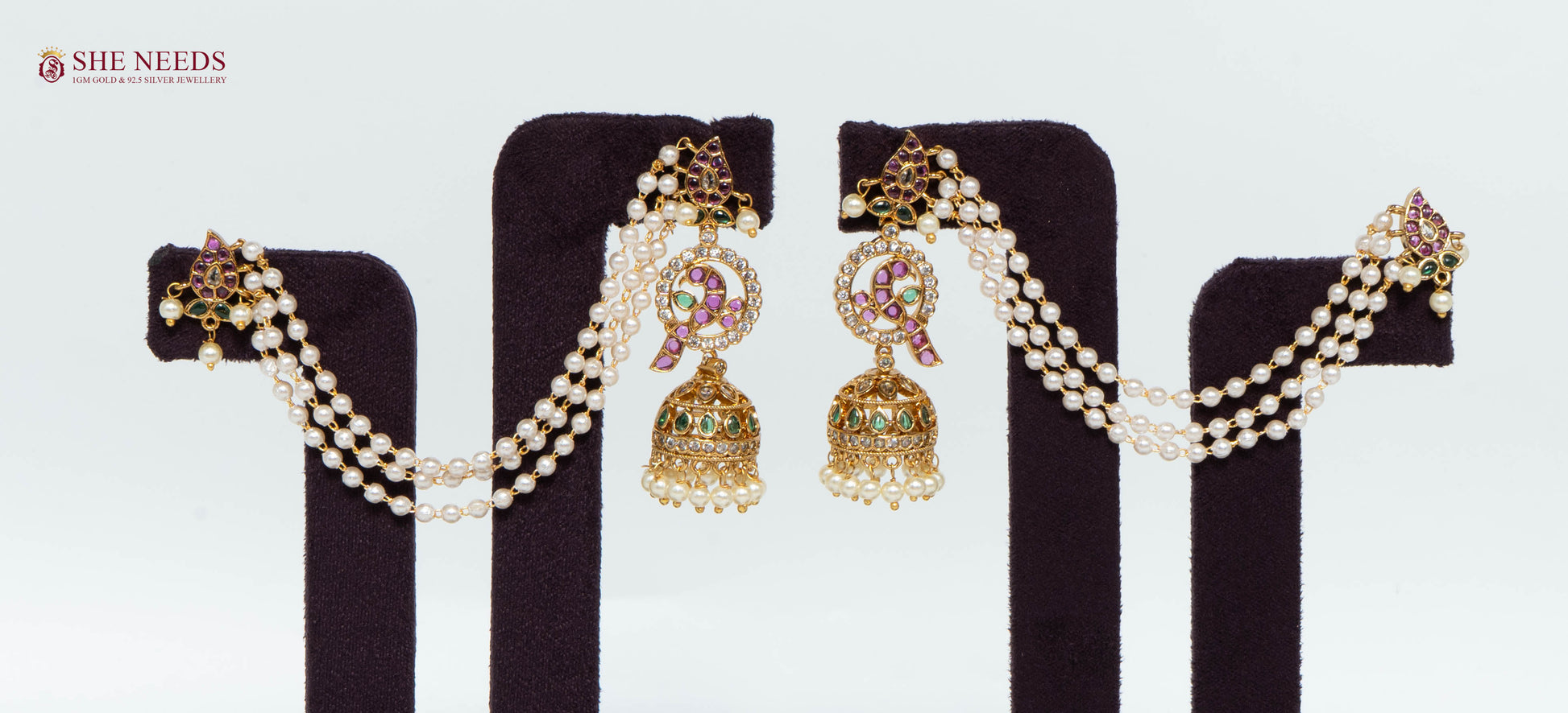Gold multicolor ear cuff jhumka earrings with triple white pearl chains, pink and green stones, American Diamond stones, and pearl drop jhumkas displayed as a pair.|She Needs Jewellery

