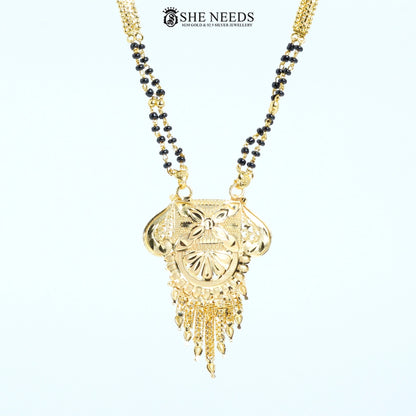 Close-up of Kamalini Gold Plated Traditional Mangalsutra featuring an engraved floral pendant with tassel detailing and a classic black bead chain.|She Needs Jewellery
