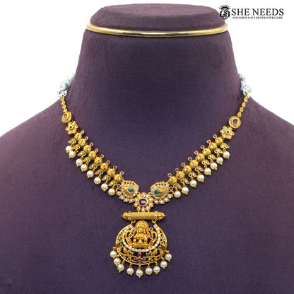 Close-up of Lakshmi motif temple necklace with green and ruby stones and pearl detailing|She Needs Jewellery
