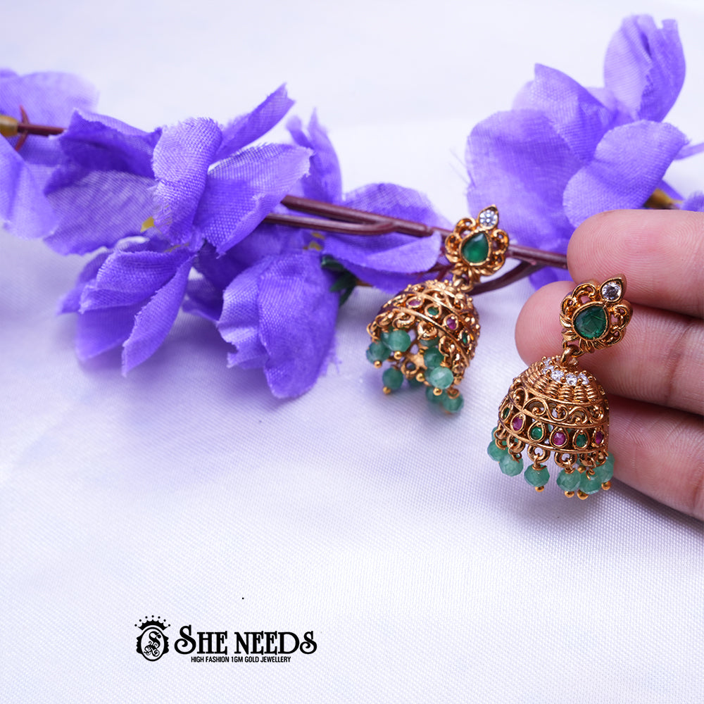 Antique gold Mayura jhumka earrings featuring green teardrop stones, colorful kemp stone detailing, intricate dome craftsmanship, and green bead drops.|She Needs Jewellery
