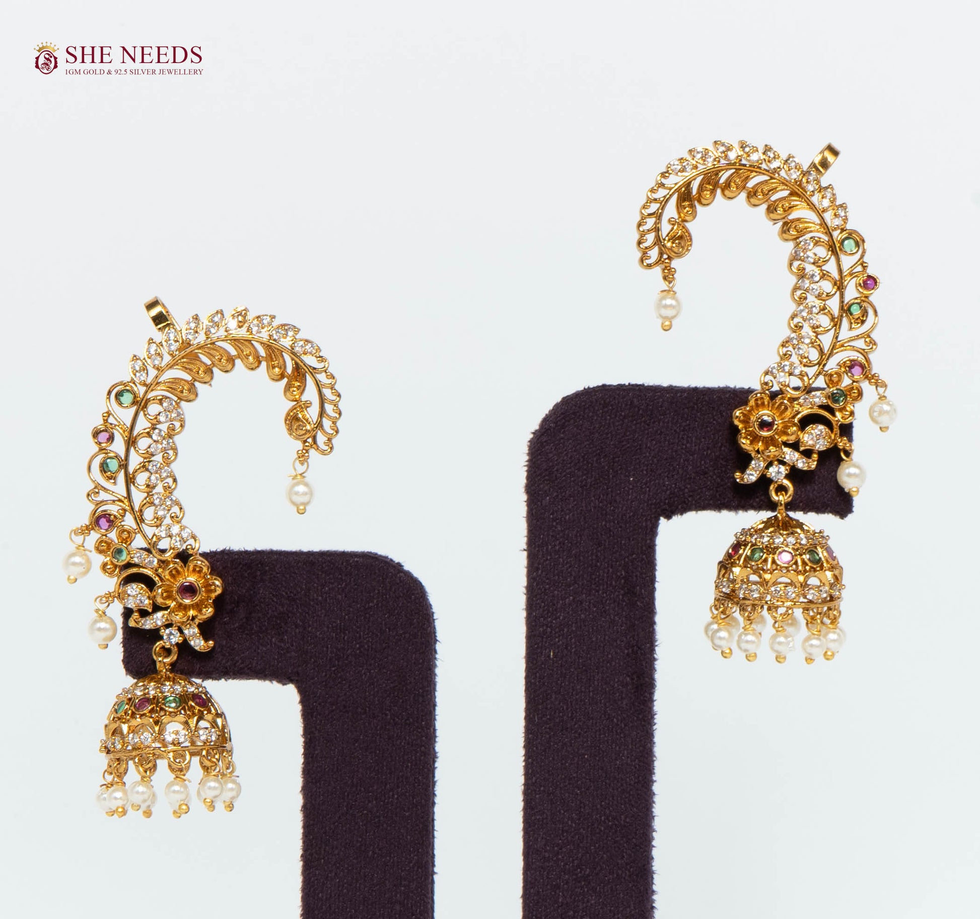 Mayurika peacock design gold-plated jhumka earrings with American Diamonds, ruby and green stones, and pearl drops