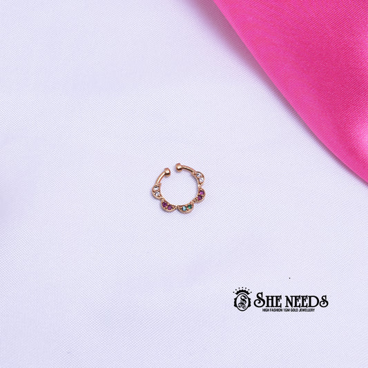 Antique gold hoop nose pin featuring a floral petal motif with sparkling white CZ stones, ruby-pink accents, and emerald-green stones on a white and pink fabric background.|She Needs Jewellery
