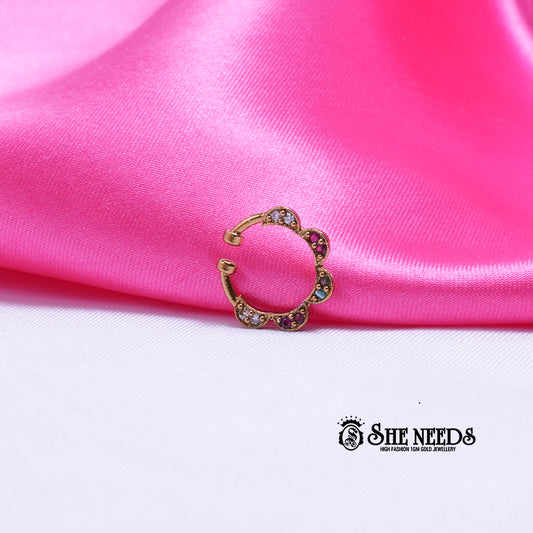 Antique gold hoop nose pin featuring a floral petal motif with sparkling white CZ stones, ruby-pink accents, and emerald-green stones on a white and pink fabric background.|She Needs Jewellery
