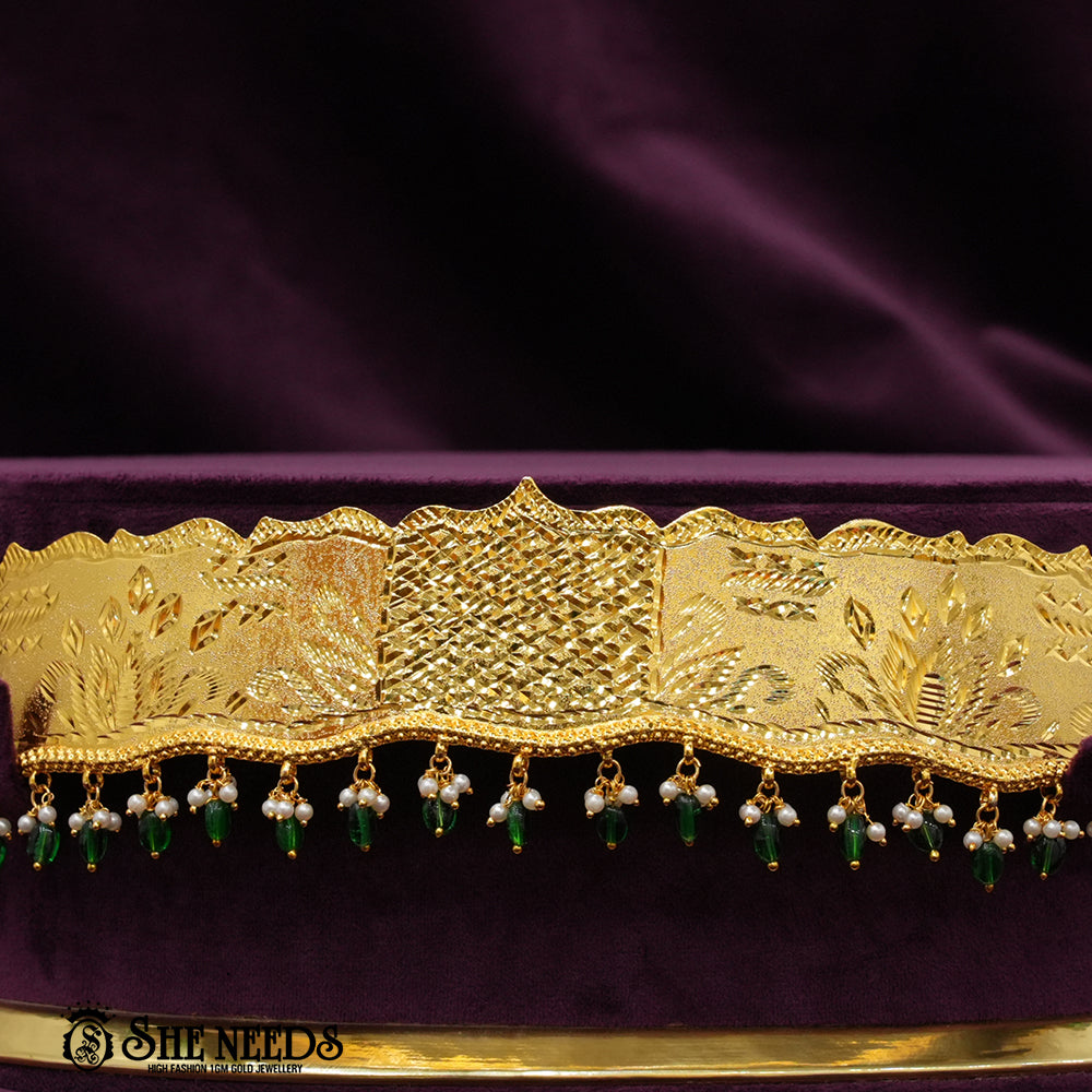 Ethnic gold bridal waist jewelry (vaddanam) with pearl and red bead dangles.