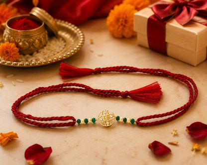 Traditional green bead Rakhi with gold-tone decorative motif and red braided thread on white background.