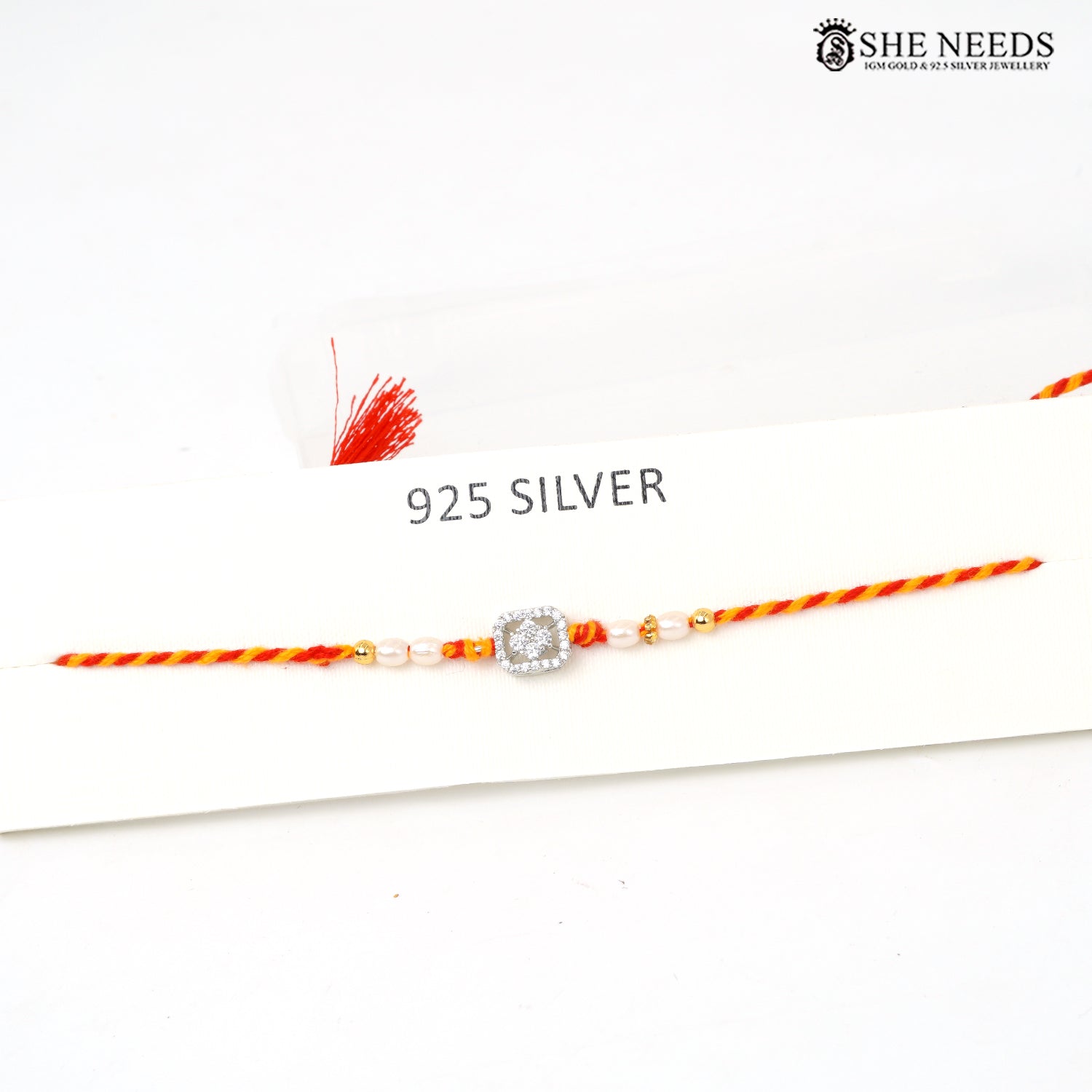 Elegant silver Rakhi with pearl beads, sparkling CZ stones and red-yellow braided thread for Raksha Bandhan.
