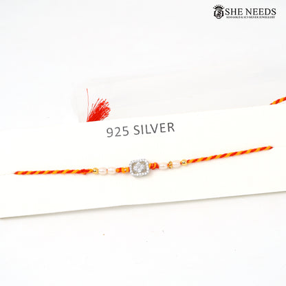 Elegant silver Rakhi with pearl beads, sparkling CZ stones and red-yellow braided thread for Raksha Bandhan.
