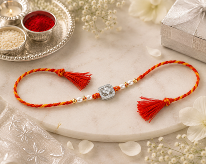 Elegant silver Rakhi with pearl beads, sparkling CZ stones and red-yellow braided thread for Raksha Bandhan.