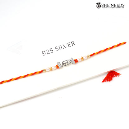 925 silver VEERA name Rakhi with pearl beads, sparkling stone accents and red-yellow braided thread.