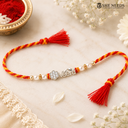 VEERA personalized 925 silver Rakhi with floral CZ motif, pearl beads, gold-tone accents, red-yellow twisted thread and red tassels.