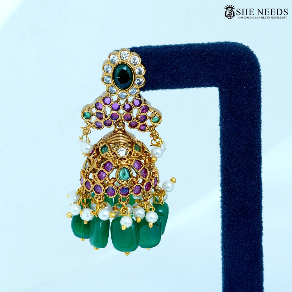Close-up of Padmika Antique Gold Temple Jhumka Earring showcasing a lotus-inspired floral design with ruby-colored stones, American Diamonds, pearl accents, and green bead drops.|She Needs Jewellery
