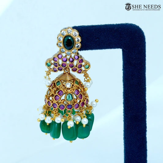 Close-up of Padmika Antique Gold Temple Jhumka Earring showcasing a lotus-inspired floral design with ruby-colored stones, American Diamonds, pearl accents, and green bead drops.|She Needs Jewellery
