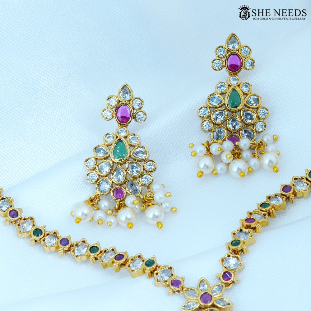 Close-up of Pushparaga Gold Plated American Diamond Pearl Jhumka Earrings featuring floral design with ruby, green, and white stones finished with elegant pearl drops.|She Needs Jewellery
