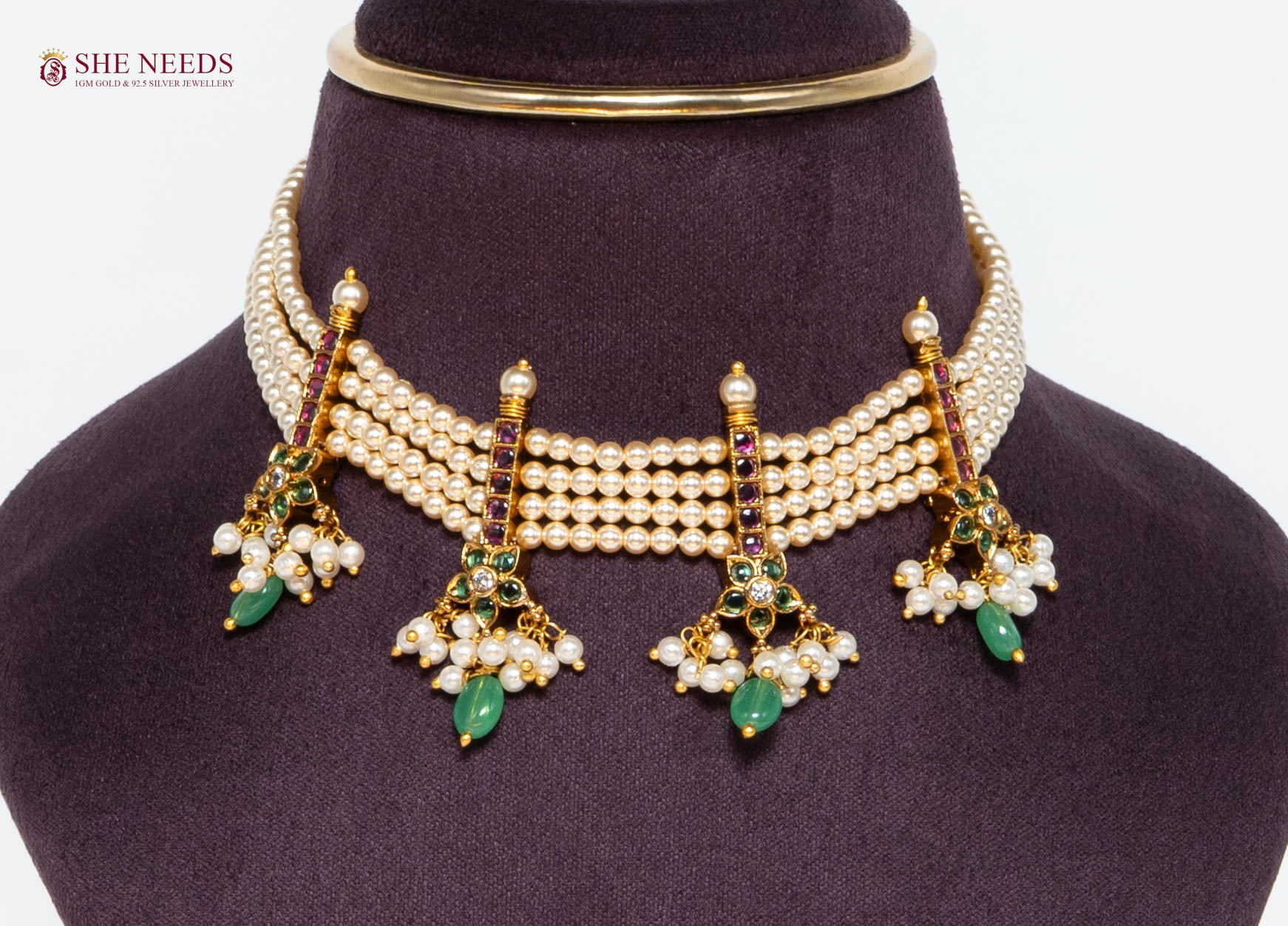 Rajnandini multi-layer pearl bridal choker necklace with green gemstone drops, ruby accents, floral motifs, and gold-plated finish