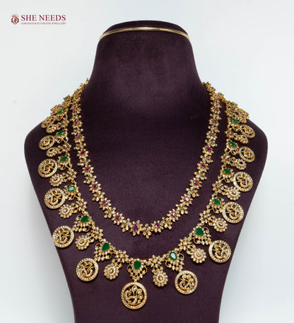 Royal Antique Lakshmi Long Haram Necklace Set with Lakshmi Coin Motifs, Ruby and Emerald Stones, Matching Earrings, and Antique Gold Finish