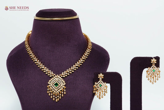 Gold-plated Royal Emerald Diamond Tassel Necklace Set with American diamonds, emerald green center stone, matching chandelier earrings, and elegant bridal pendant.|She Needs Jewellery
